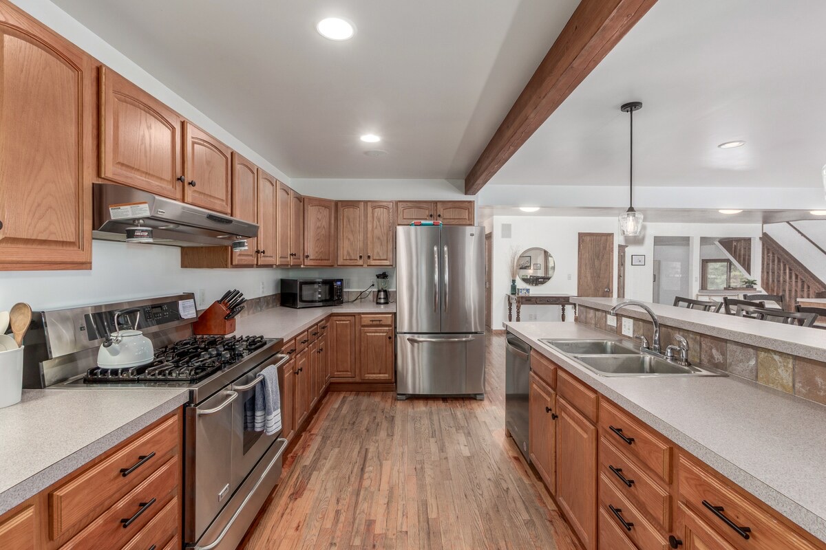 Chef's kitchen with gas range, stainless appliances, and beam ceiling